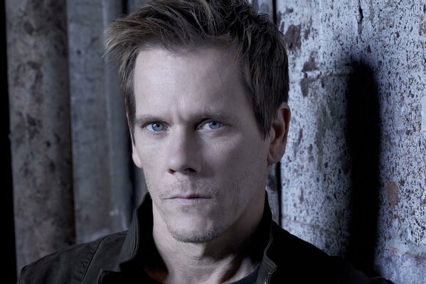 Retrato de Kevin Bacon contra una pared gris