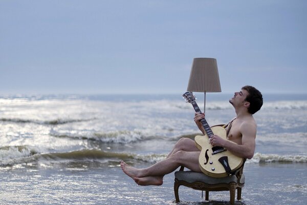A man plays a guitar by the seashore
