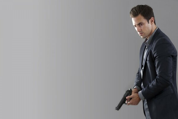 A man in a suit holds a gun