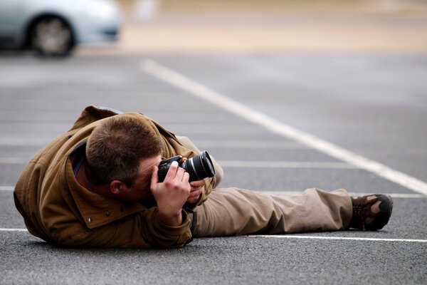 Uomo che fotografa in posizione sdraiata