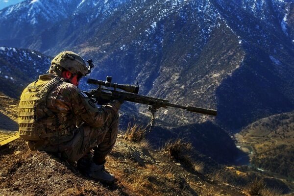 Военный снайпер сидит в горах