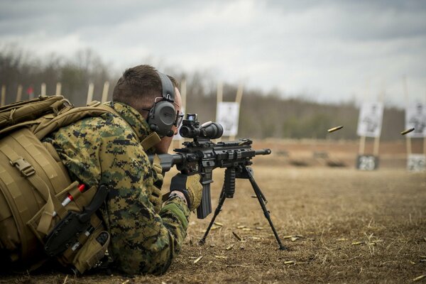 A man in a military uniform with a gun is lying on the ground