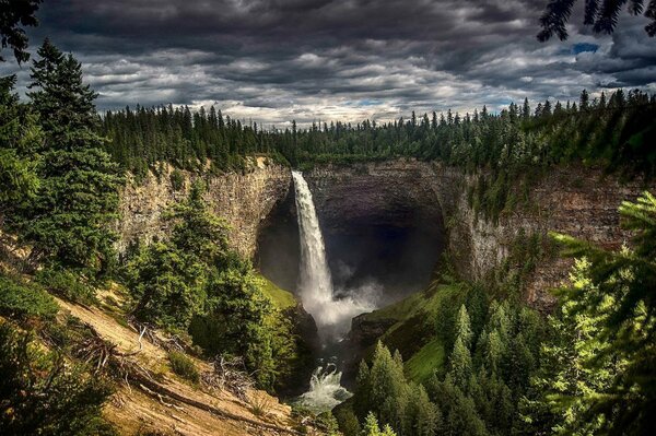 Cielo nublado. Cascada entre las rocas