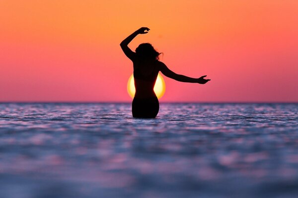 Silhouette of a girl on the sea at sunset