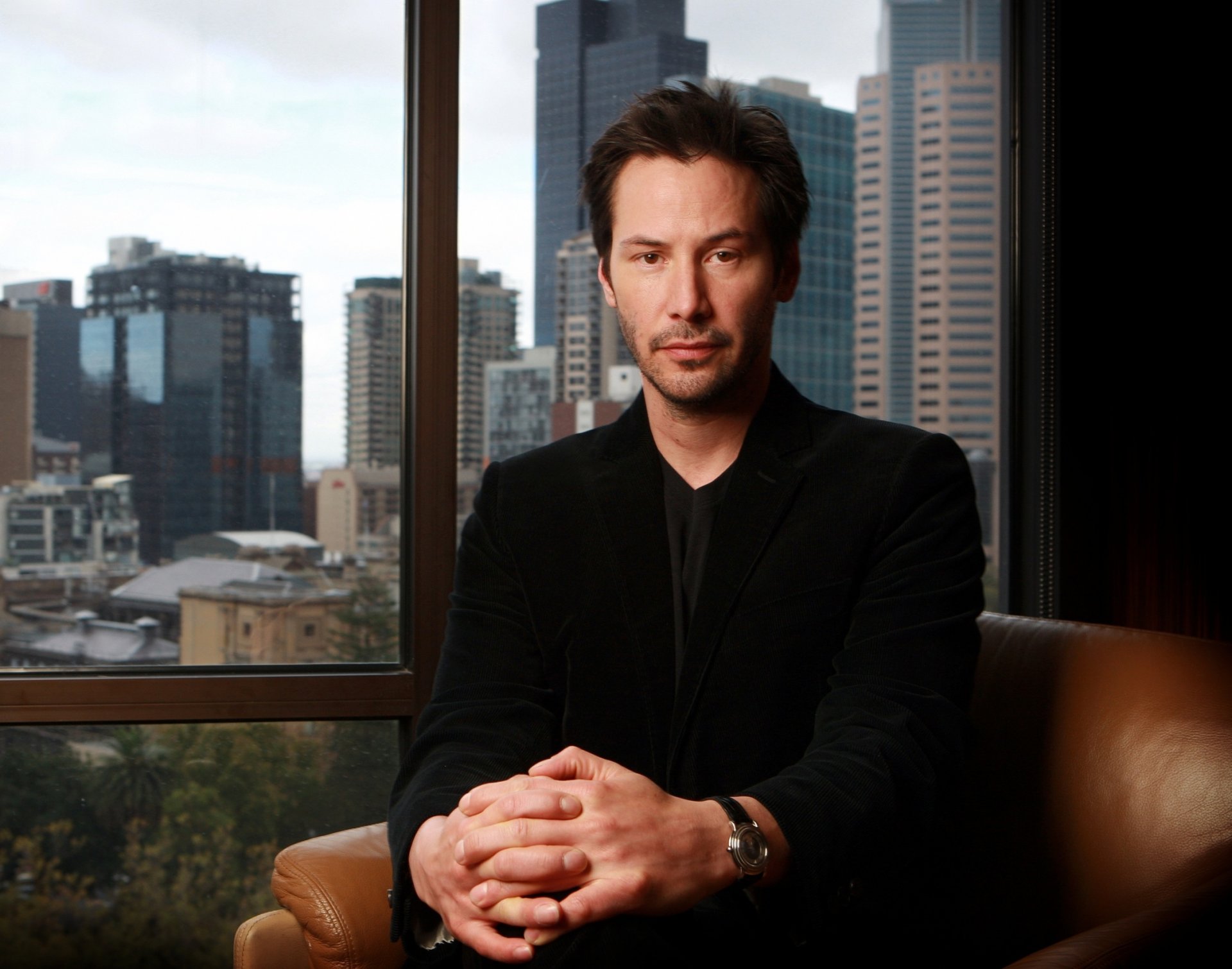 keanu reeves aktor siedzi krzesło okno widok miasto