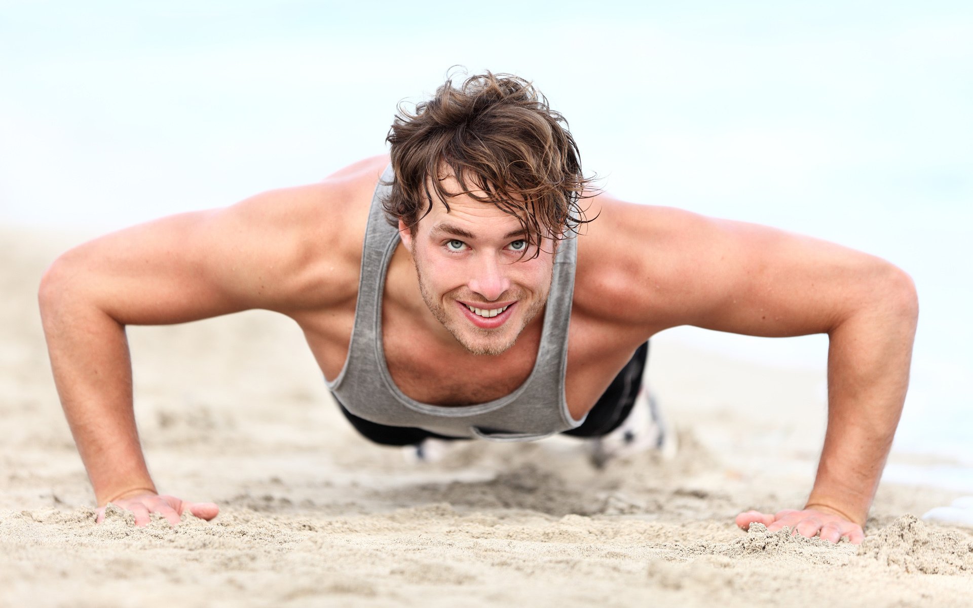 homme push-ups muscles sourire plage sable