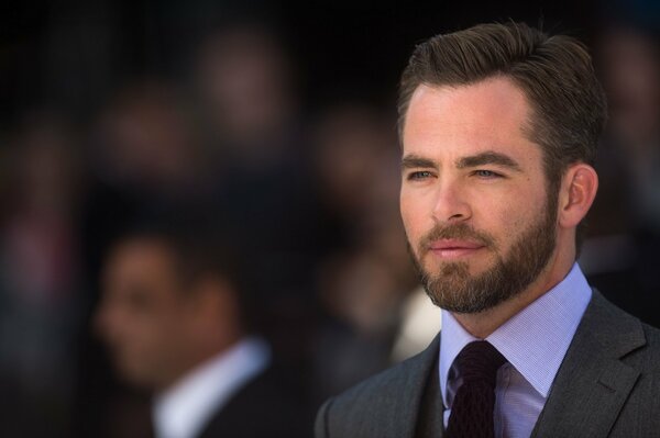 A bearded actor in a tie and a suit