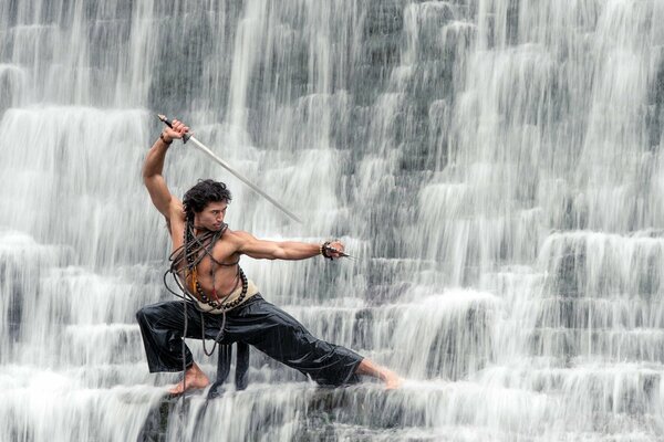 Chico en una cascada con un sable muestra Kung Fu