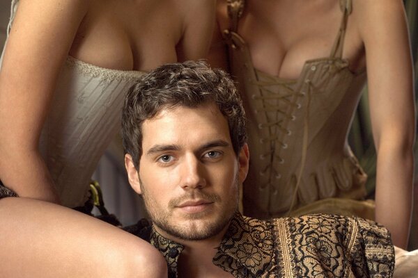 The actor of the Tudors series Henry Cavill and two ladies in corsets