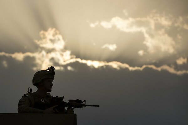 A soldier on duty with a gun on the background of the night sky