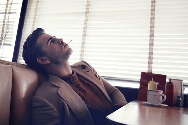 A guy in a cafe with a cigarette and coffee