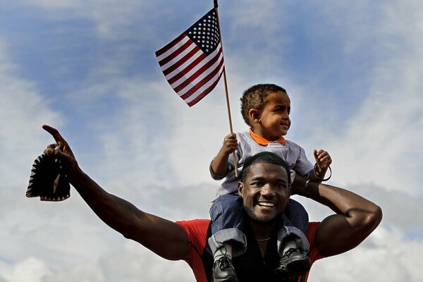 A child with a flag around a man s neck