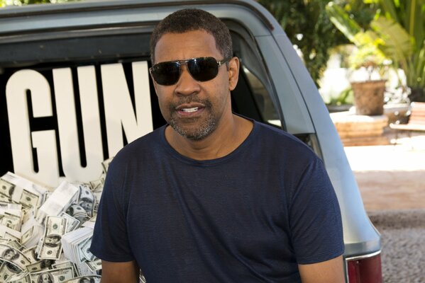 Acteur Denzel Washington dans des lunettes noires sur fond de voiture