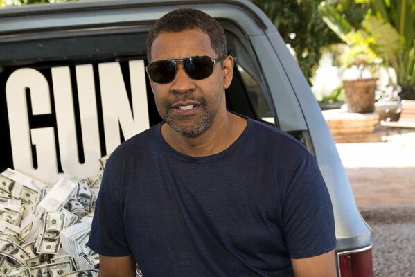 Aktor Denzel Washington w czarnych okularach na tle samochodu