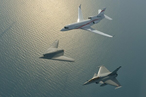 Drei verschiedene Flugzeuge fliegen über das Meer