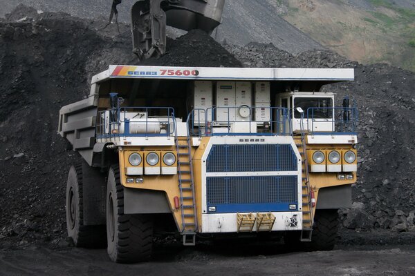 Camion à benne basculante en cours de travail dans le charbon et la poussière