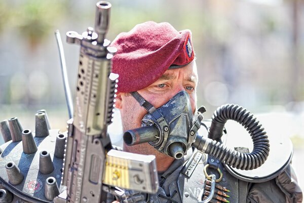 A soldier in a beret with a machine gun and a mask