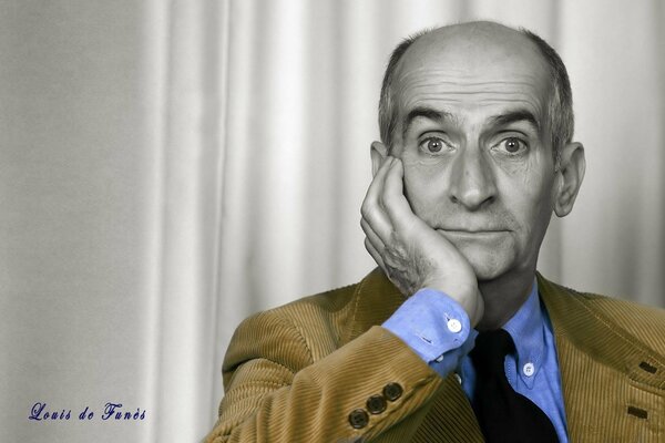 Porträt von Louis de Funes in Grautönen in einer goldenen Cordjacke und einem blauen Hemd