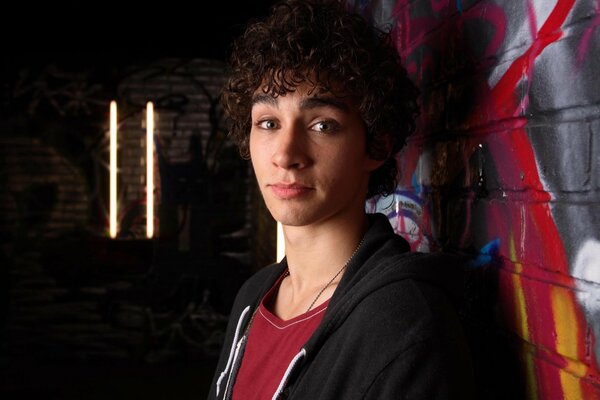 Curly-haired guy near the graffiti wall