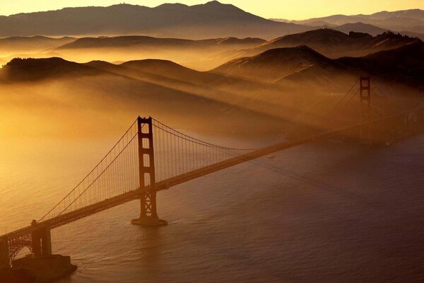 Most nad zatoką łączy dwa brzegi, widać piękne góry we mgle