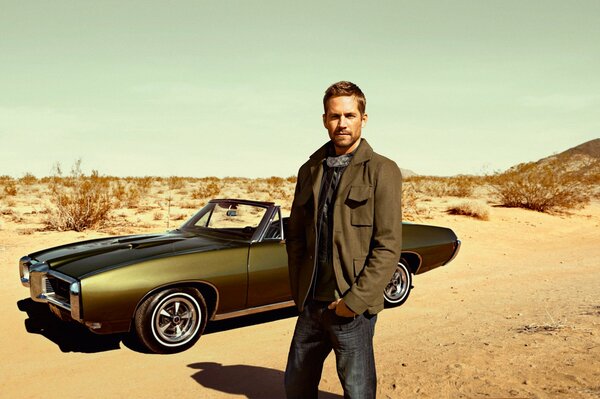 A man in the desert with a green car