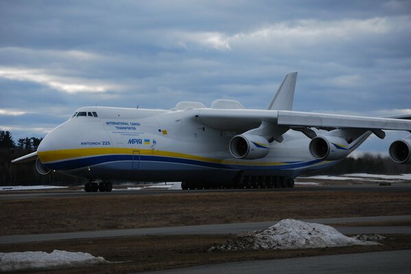 A large plane is standing on the runway against the background of the sky with clouds