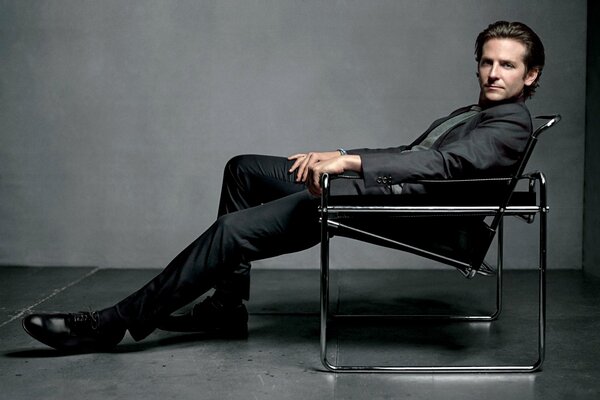Aktor Bradley Cooper w garniturze na krześle