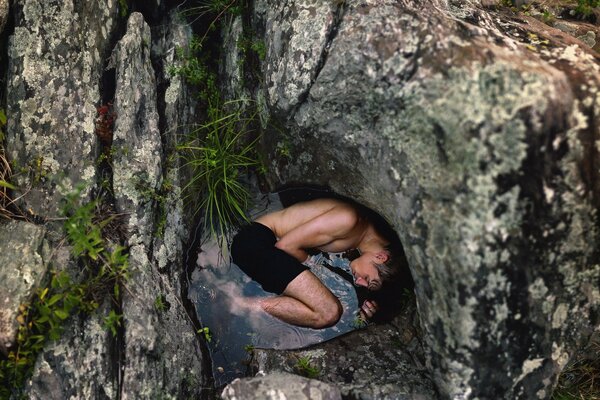 Au milieu des rochers dans le lac se trouve un homme en short