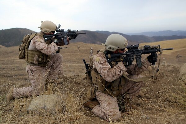 Two American soldiers with weapons in the steppe