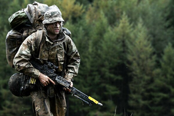 A soldier with a gun on the background of a forest