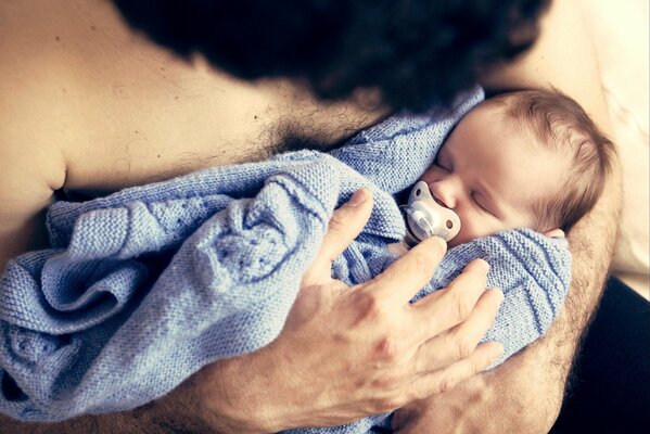 Ein Mann mit einem Baby in seinen Armen, der schläft