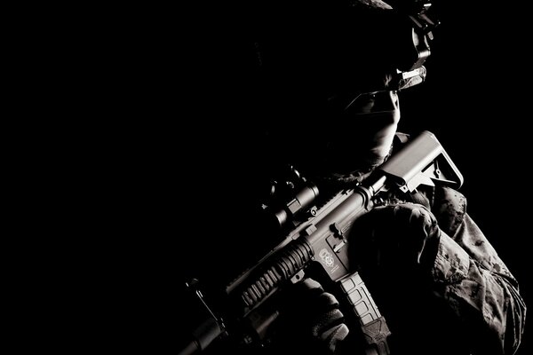 A soldier with a gun in his hands on a black background