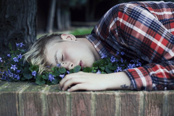 A guy sleeping among violets under a tree