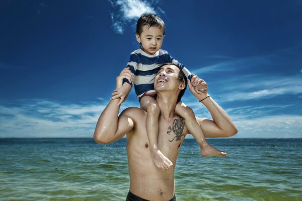 Vater und Sohn auf den Schultern am Meer