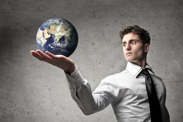 A guy in a tie holding a globe in the palm of his hand