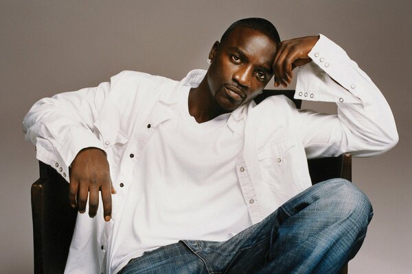 Piosenkarka Akon w białej koszuli w fotelu