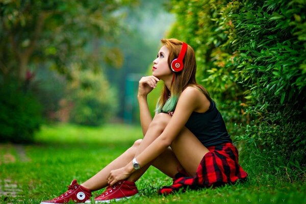 A model in headphones and sneakers poses on the grass