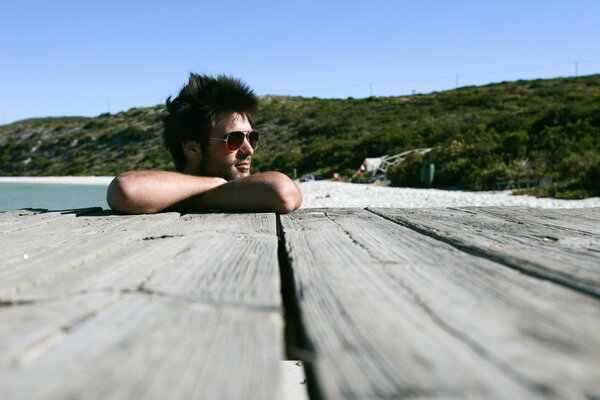 A guy with a gorgeous head of hair is relaxing on the beach