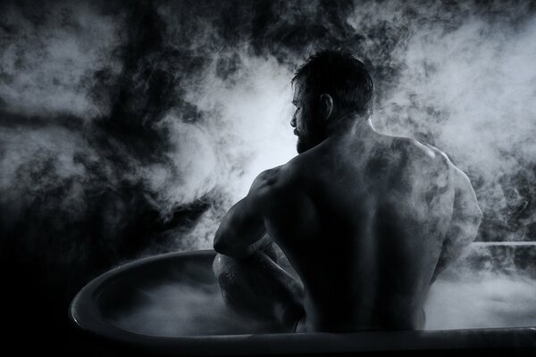 Мускулистый мужчина сидит в горячей ванне