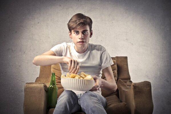 Le gars avec des frites est assis sur une chaise