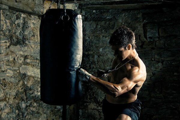 El chico entrena los músculos con la ayuda de un saco de boxeo