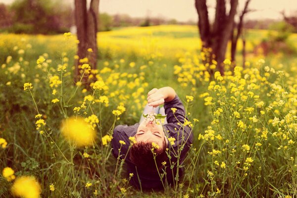 The guy is lying in a field in nature