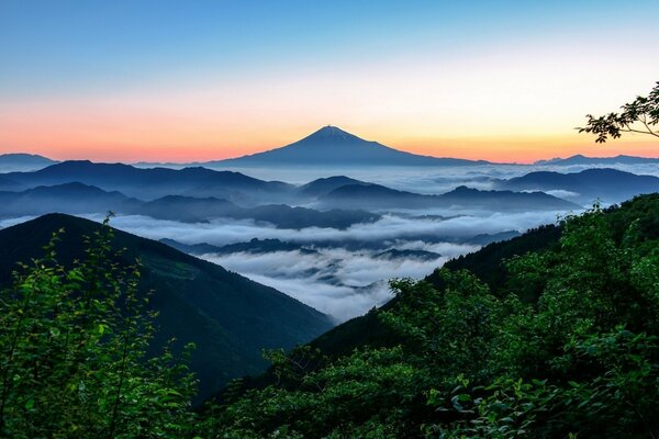 La nebbia scende dalle montagne sullo sfondo del tramonto