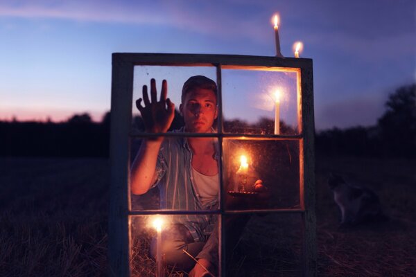 Il ragazzo con la candela guarda attraverso la finestra