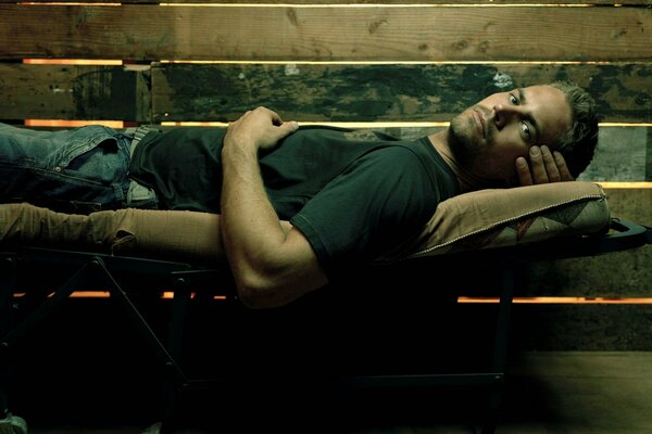 Мужчина актёр Пол Уокер лежит на раскладушке