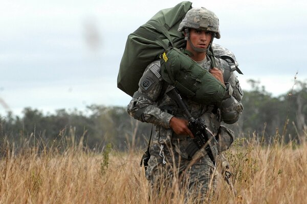 Un soldat avec une mitraillette marche sur le terrain