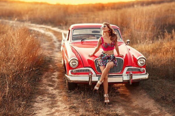 Fille sur une voiture rétro rouge