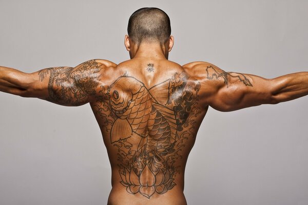 Tattoo in the form of a fish on the relief back of a man