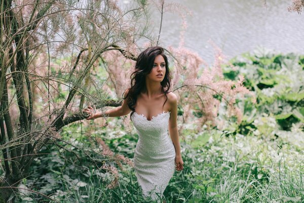 Morena en vestido blanco en la naturaleza