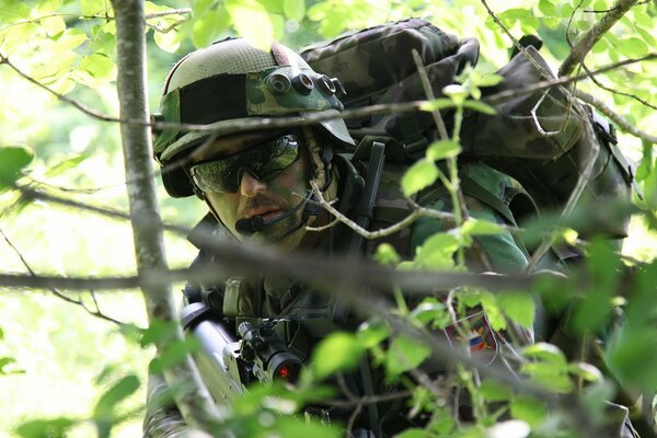 A soldier in the forest behind the branches